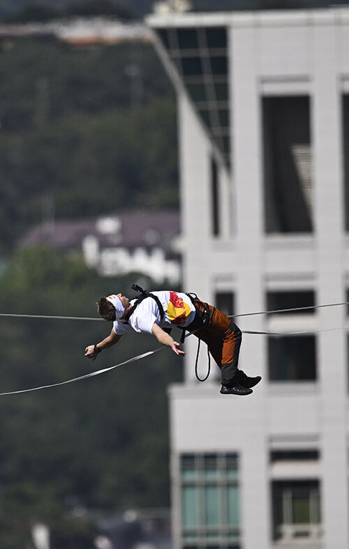 Slackline athlete Jaan Roose performs stunts in the air above Sejong-daero, in front of Cheonggye Plaza in Seoul, on the 1st, walking and showcasing various skills while balancing on a tightrope. (Photo: Yonhap News)