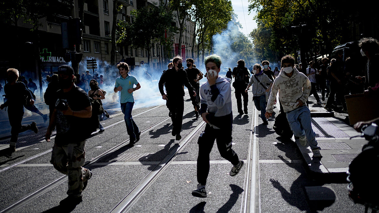 Students participating in a protest run through tear gas in Lyon, France, on October 2 (local time).