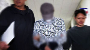 모자이크 처리된 피의자가 양옆의 관계자들에게 붙잡혀 복도를 이동하는 모습