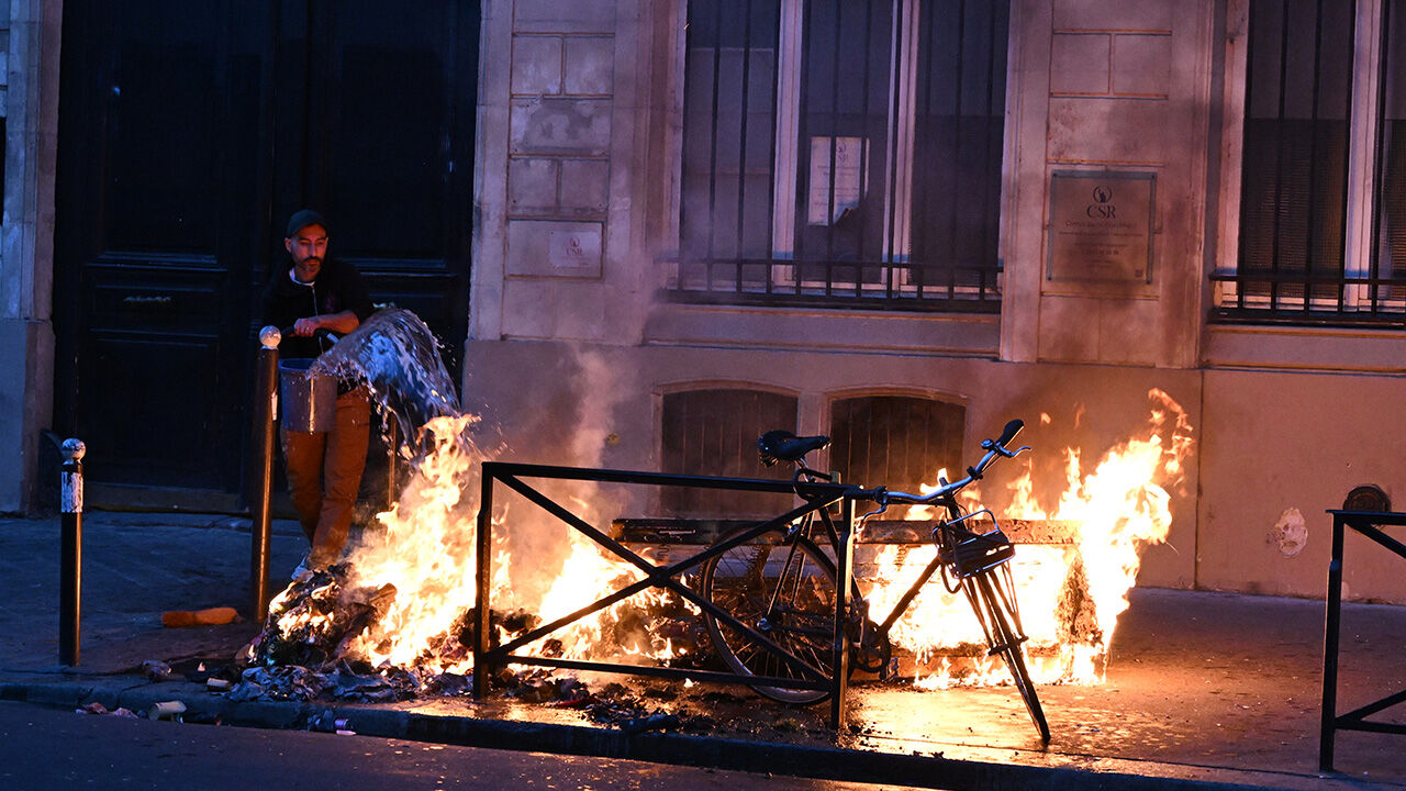 Amid clashes between protesters and police in Paris, France, a man tries to put out a fire. (Photo: AP, Yonhap)
